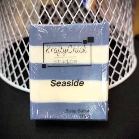 Handmade bar soap on black table against white mesh. Soap is blue and white striped.