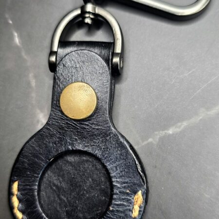 Black leather Apple AirTag case with orange stitching on a lobster clasp keychain.
