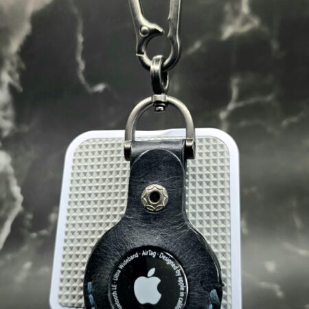 Black leather Apple AirTag holder stamped with a pair of navy handled guns with blue stitching