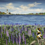 A print of calico cat in a field of lupines looking across the harbour at a lighthouse and small shanties along the shore. The sky is blue with fluffy clouds.