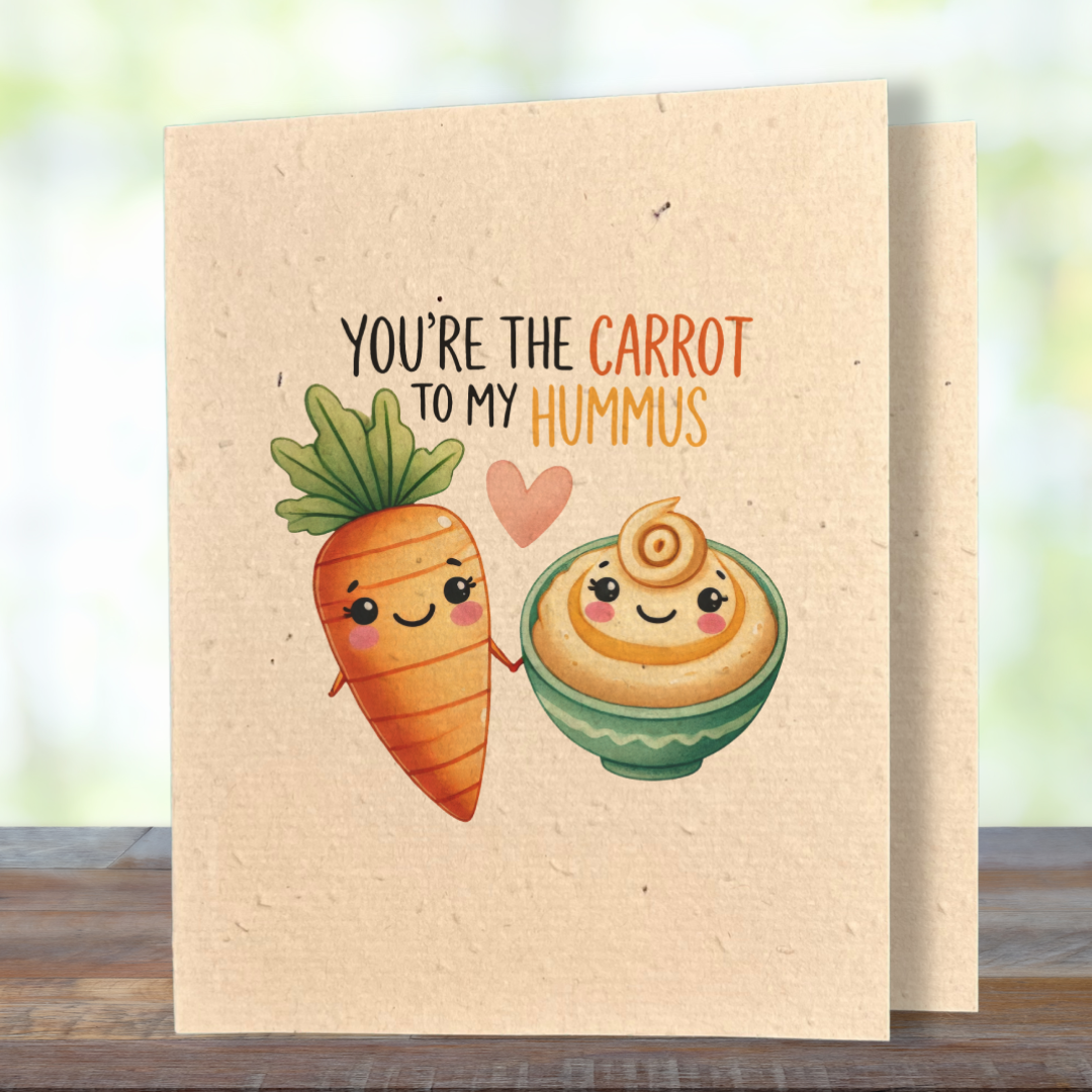 plantable greeting card, natural coloured paper, embedded with wildflower seeds, an image in kawaii style of a carrot and a bowl of hummus holding hands, the sentiment reads you're the carrot to my hummus.