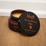 Idozi Hair Conditioning Butter in an amber jar with black lid and saffron branding, open to reveal rich conditioning formula for dry, textured, and natural hair – deep moisture hair care treatment.