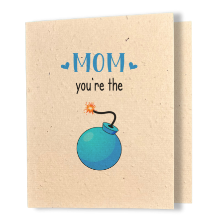 A greeting card printed on textured kraft seed paper. The card features the word mom is blue capitals with a heart of each side of the word. Then is black smaller text below are the words you’re the, then below that is an illustration of a blue bomb that has a lit fuse.