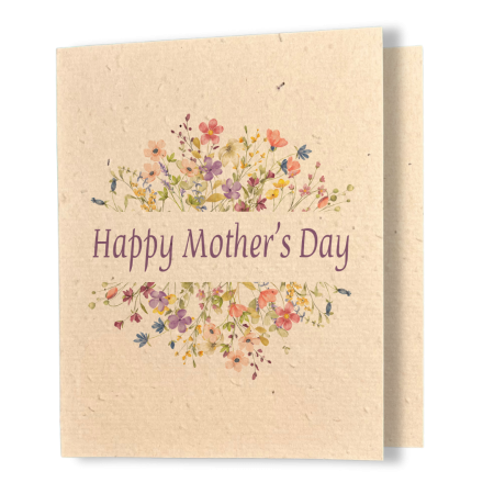 A greeting card printed on textured kraft seed paper. The card features two arching clusters of delicate watercolour wildflowers in shades of pink, purple, coral, yellow, and blue, framing the text "Happy Mother's Day" in elegant purple serif lettering at the centre.