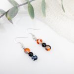 Dangle earrings with orange-gray-black agate beads, black onyx pearls, sterling silver spacer beads, and sterling silver hooks.