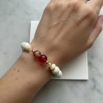 Stretch bracelet of white turquoise beads with golden Swarovski accents, 14K gold‑filled spacer beads, and red‑yellow crackle centerpiece beads