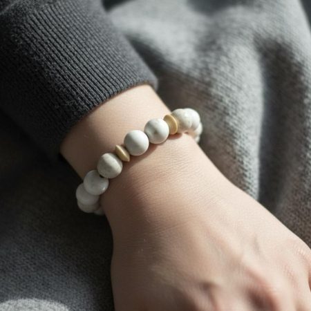 Stretch bracelet of white magnesite beads accented with beige wood bicone beads.